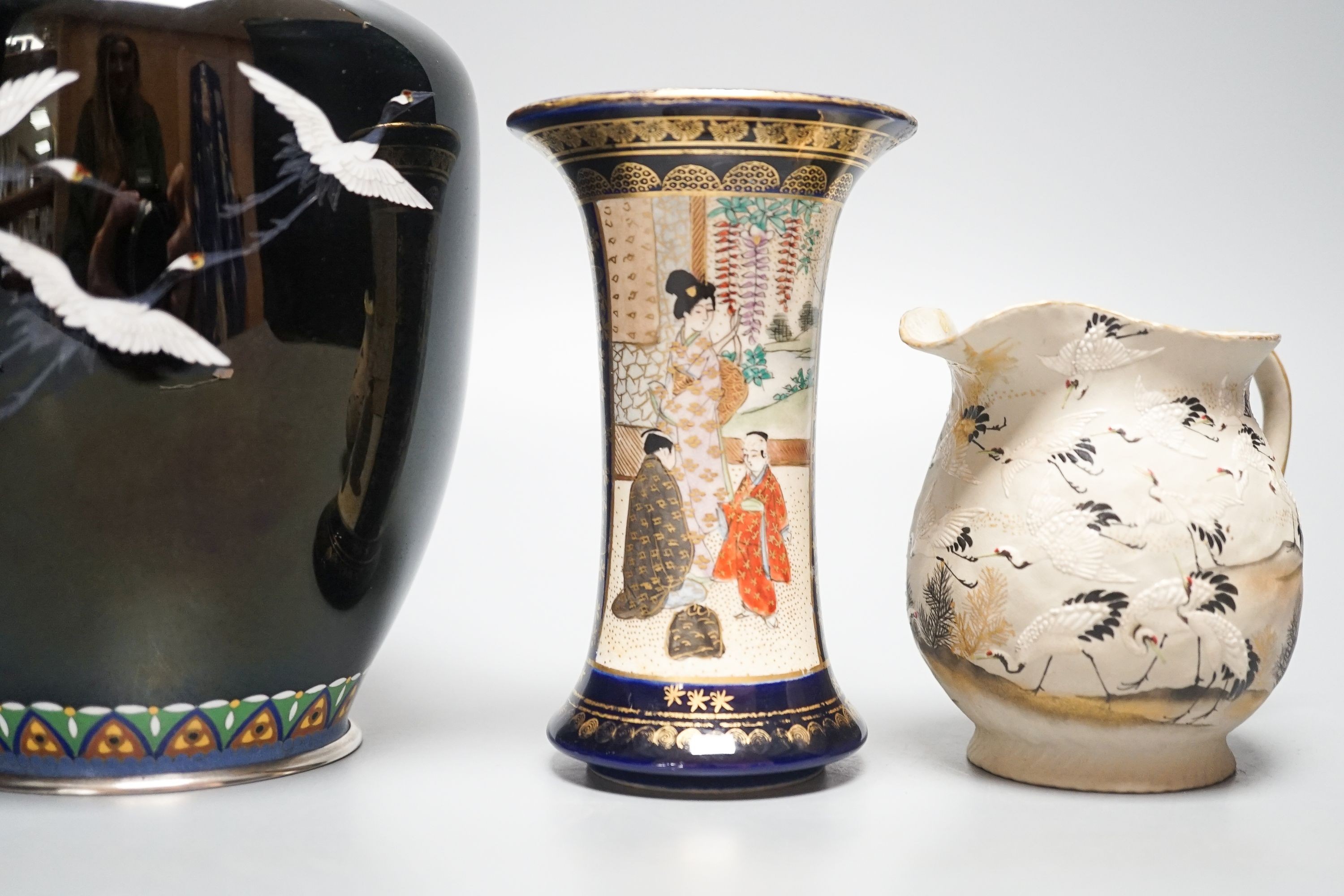 A Japanese black ground ‘cranes’ cloisonné enamel vase, 18.3cm, a Satsuma pottery vase and a crane decorated jug (3)